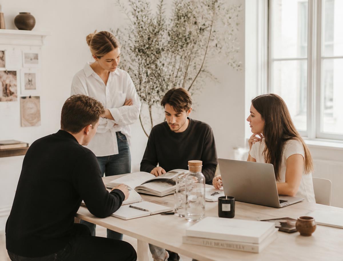 Small creative team collaborating around a light wooden table in a bright studio